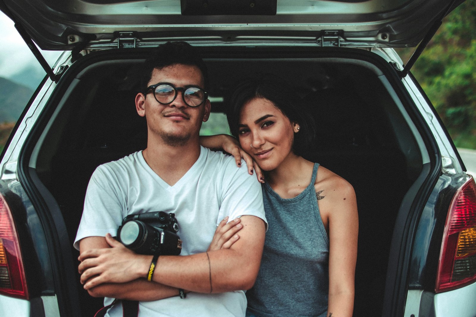 woman leaning on man's shoulder beside car during daytime